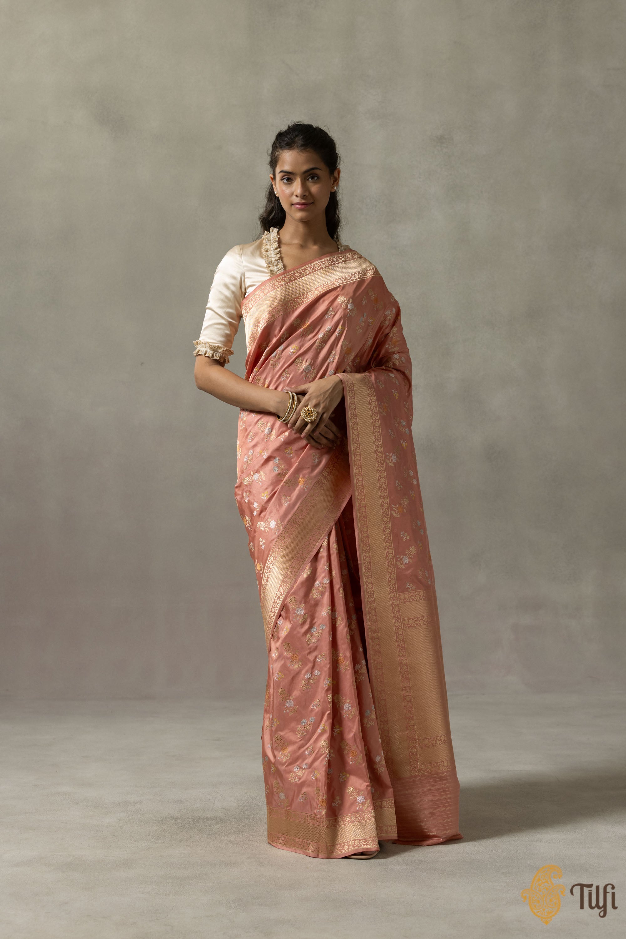 Close-up of the pastel coral peach Banarasi saree showcasing detailed Meenakari floral bootis.