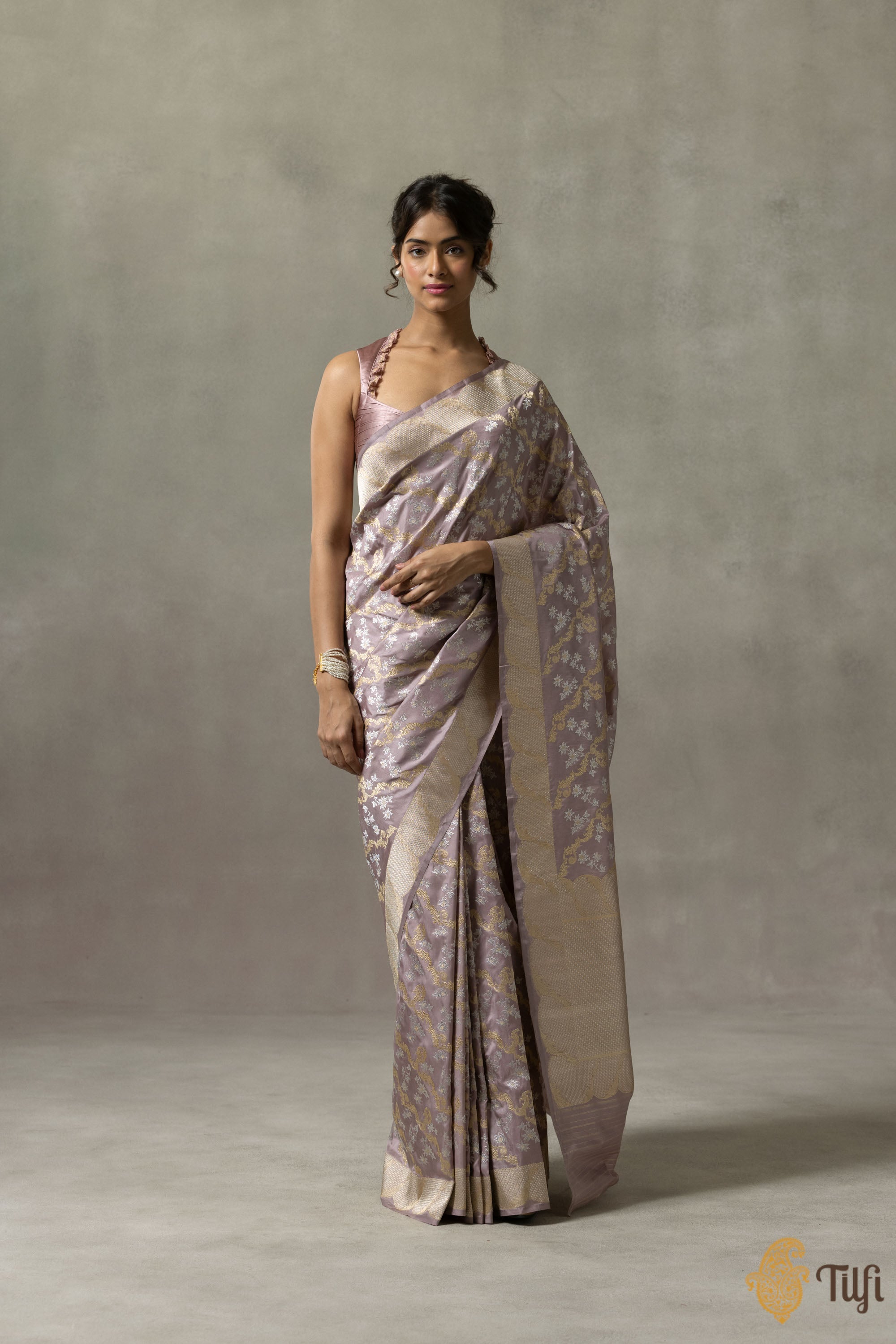 Banarasi saree draped elegantly on a model, highlighting the intricate zari work and pastel mauve pink color.
