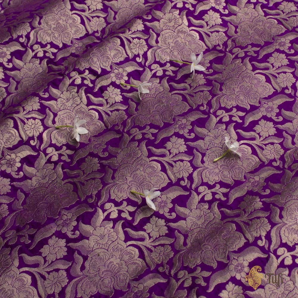 Close-up of vibrant purple Katan silk Banarasi fabric showcasing intricate zari work and floral patterns.